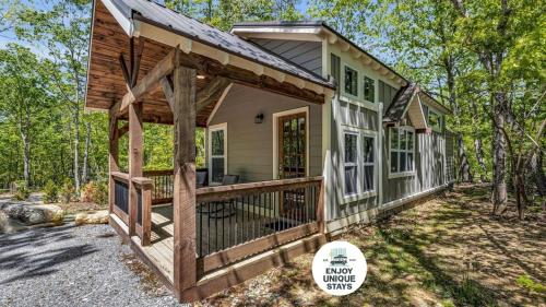 a tiny house with a porch in the woods at Menlo GA Tiny Home Experience in Rising Fawn