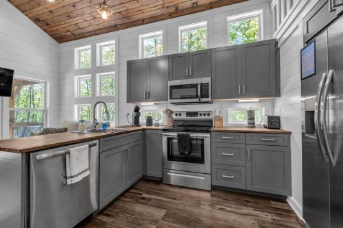 a kitchen with gray cabinets and stainless steel appliances at Menlo GA Tiny Home Experience in Rising Fawn