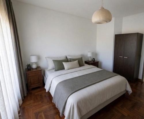 a bedroom with a large bed and a wooden floor at Humen apartamento T2 in Tavira