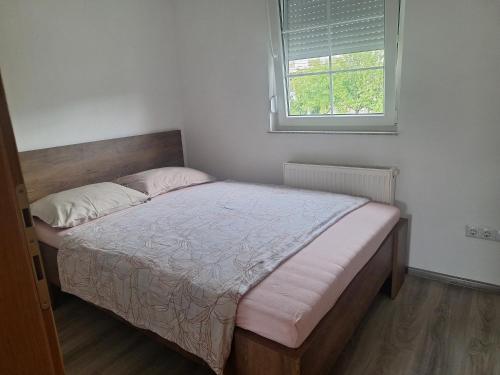 ein Bett in einem Schlafzimmer mit Fenster in der Unterkunft Apartman SELMA in Vogošća