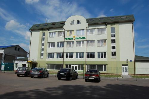 a large building with cars parked in a parking lot at Art Hotel Palma in Lviv