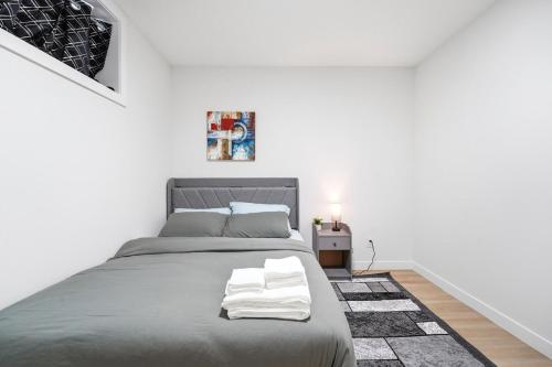 a bedroom with a large gray bed with white towels on it at Suite in Ambleton - Calgary in YYC