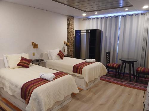 a hotel room with two beds and a table at Hotel Cristales De Sal in Uyuni