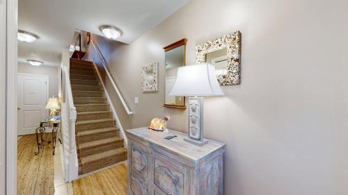 a hallway with a staircase and a lamp on a dresser at Rehoboth Crossing - 36983 Grindstone Ln in Rehoboth Beach