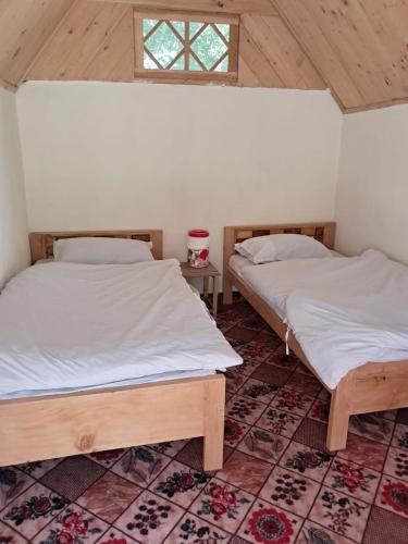 two twin beds in a room with a window at Fish Lake Park Guest House in Chitral