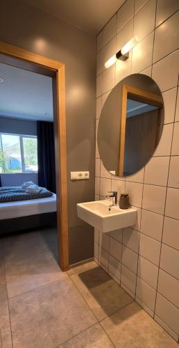 a bathroom with a sink and a mirror and a bed at Eldá apartments in Myvatn