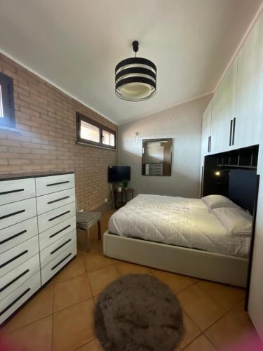 a bedroom with a white bed and a brick wall at Nenniri's house in Villamassargia