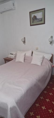 a large white bed with white sheets and pillows at Одисей in Chişinău