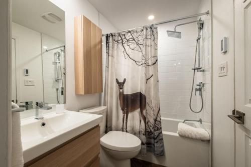 a bathroom with a toilet and a shower curtain with a fox at Simple & Luxe Condo With View in Mont-Tremblant
