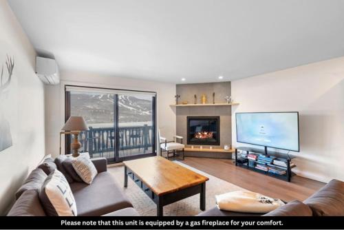 a living room with a couch and a tv at Spacious Condo with Lake and Mountain View in Mont-Tremblant