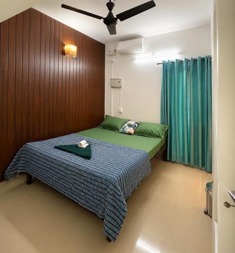 a bedroom with a bed with a green comforter at GOOD KARMA INN Apartment in Cochin