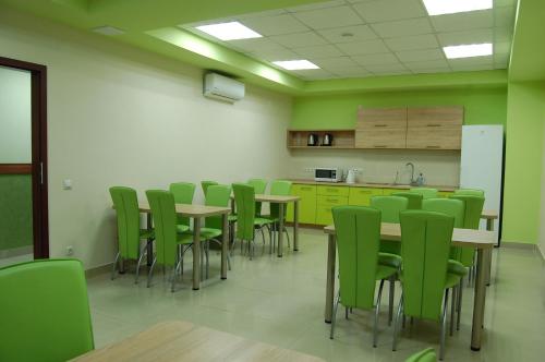 una habitación con sillas y mesas verdes y una cocina en Art Hotel Palma, en Leópolis