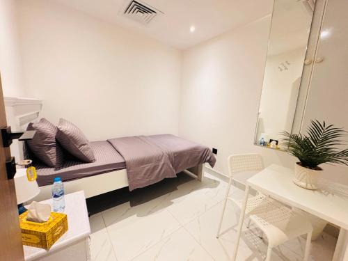 a small white room with a bed and a table at Vogue Inn in Abu Dhabi