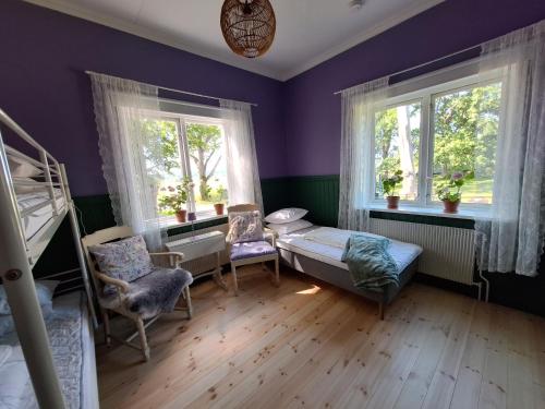 a bedroom with purple walls and two windows at Karaby Gård, Country Living självhushåll in Kristinehamn