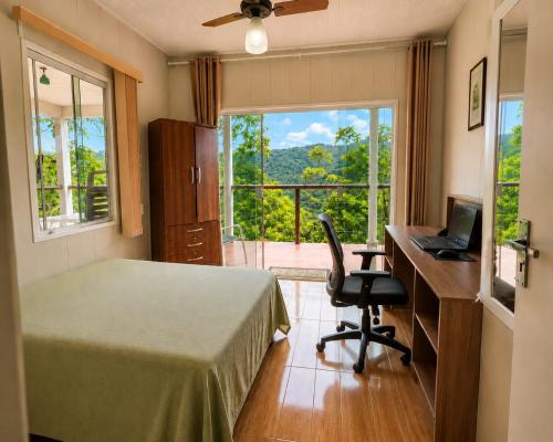 a bedroom with a bed and a desk with a laptop at CHÁCARA DOMINGOS MARTINS - SANTO GRAAL - Montanhas, Corredeiras, Piscina, Natureza e Paz in Domingos Martins