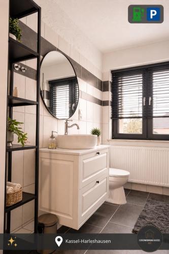 a bathroom with a sink and a mirror and a toilet at Ferienwohnung Kassel mit Ladesäule in Kassel