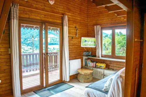 a bedroom with windows and a bed in a wooden room at Chalet entier, vue panoramique, ruisseau et sauna. in Bussang