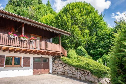 a house with a stone wall and a balcony at Chalet entier, vue panoramique, ruisseau et sauna. in Bussang