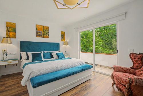 a bedroom with a blue bed and a chair at casa Jardín del sol planta alta in Tacoronte