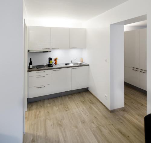 a kitchen with white cabinets and a wooden floor at Xperience-Today Eupen in Eupen