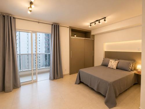 a bedroom with a bed and a large window at Studio Mobiliado no Independência 915 in Juiz de Fora
