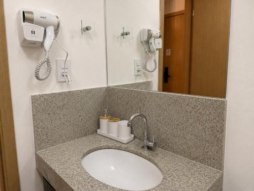 a bathroom counter with a sink and a phone at Studio Mobiliado no Independência 915 in Juiz de Fora