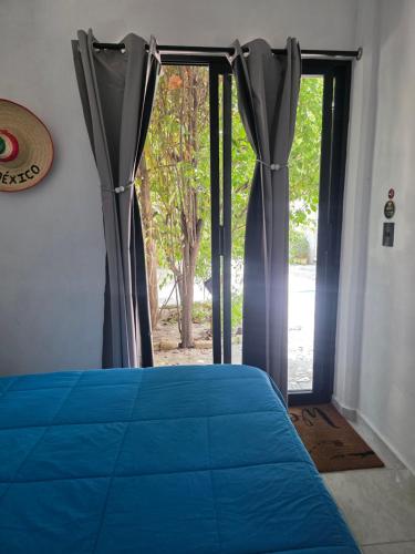 a bedroom with a blue bed and a sliding glass door at Casa Amarilla Tecámac in Santa Cruz Tecamac