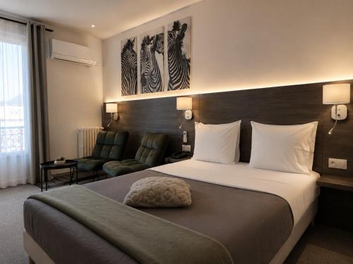 a hotel room with a bed and two chairs at Hôtel L'Alsace Gare-Sncf in Narbonne