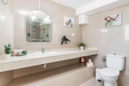 a bathroom with a sink and a toilet and a mirror at Moser Living Premium Apartments - Puerto Rico in Mogán