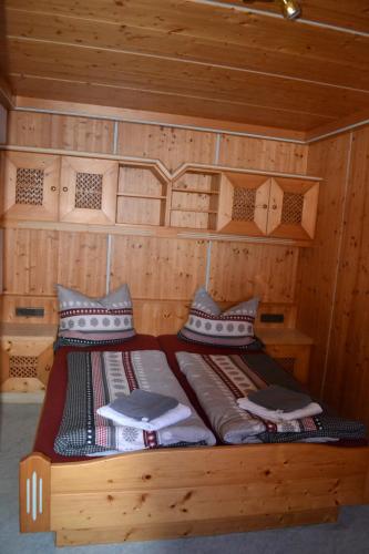 a bed in a wooden room with two pillows at Stadlbauergütl in Leogang