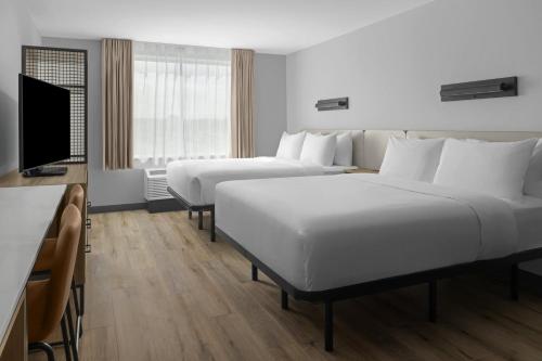 a hotel room with two beds and a flat screen tv at StudioRes by Marriott Clearfield Layton in Clearfield