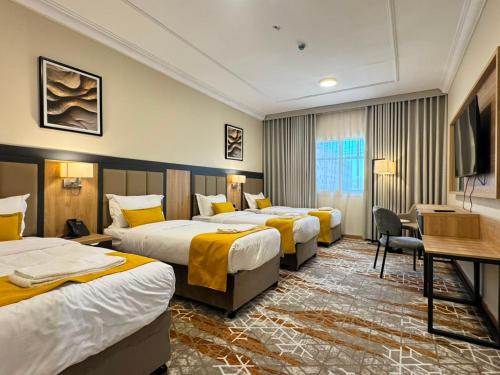 a hotel room with three beds and a desk at فندق بارك برايم - Park Prime Hotel in Mecca