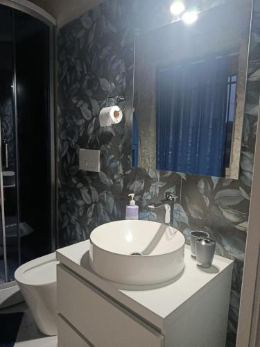 a bathroom with a sink and a toilet and a mirror at La casa di Jacopo in Modica