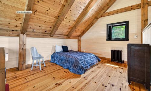 a bedroom with a bed and a chair in a room at Maison ULTIMA ÉCO in LʼIslet