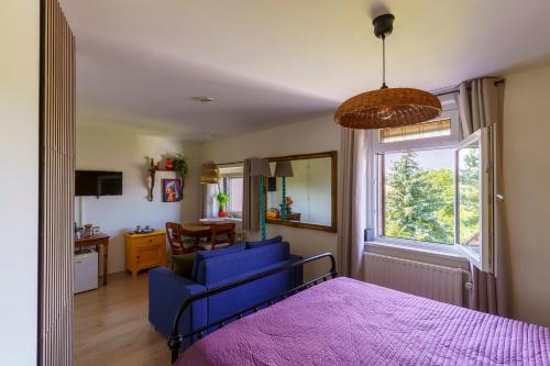 a bedroom with a bed and a blue couch and a window at Droom op de Vijlenberg in Vijlen