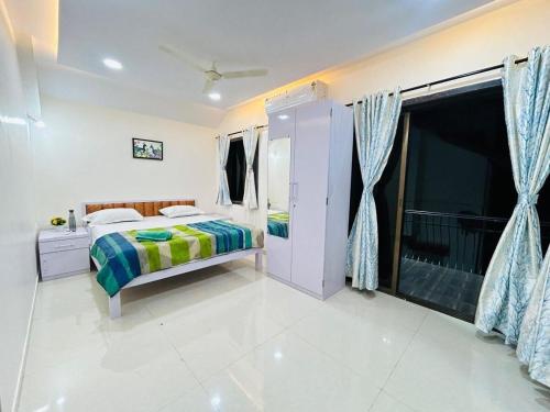 a white bedroom with a bed and a balcony at Orchid Villa - The Dream Stays ll Big Pvt Pool ll 3Ac room ll Wi-Fi ll Tv in Lonavala