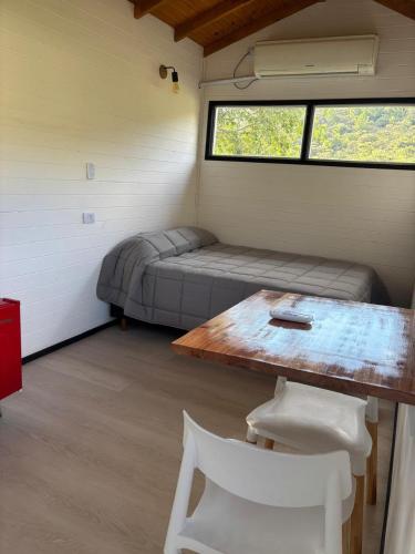 a room with a bed and a table and a window at TiniHouse AguadePiedra in Villa Giardino