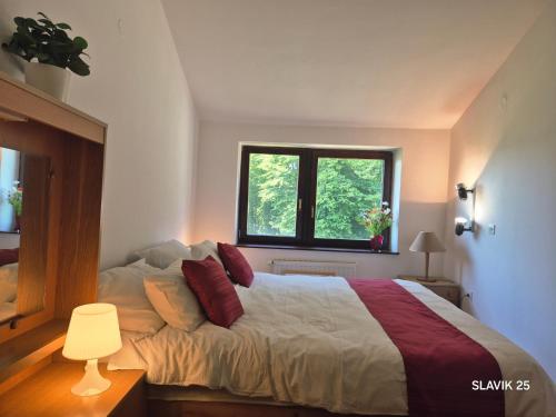 a bedroom with a bed with red pillows and a window at Kuća za odmor SLAVIK in Daruvar