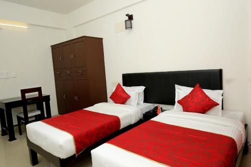 two beds in a hotel room with red pillows at Hotel O Technopark Formerly Le Frank in Trivandrum