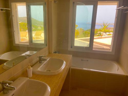 a bathroom with two sinks and a tub and a window at Ibiza 7th Heaven Villa in Sant Josep