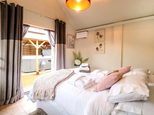 a bedroom with a white bed and a window at Tiny Home with Hot Tub in Roydon