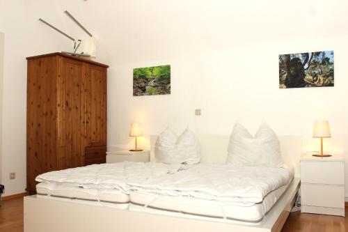 a white bed in a room with two lamps at Hexnquartier in Braunlage