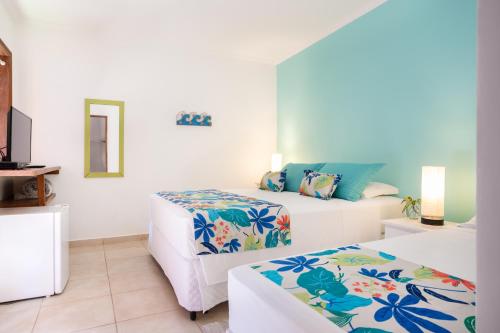 a hotel room with two beds and a tv at Pousada Casalinda Camburi in Camburi
