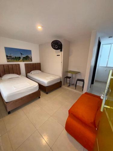 a room with two beds and a couch and a window at Villalba Boutique Hotel in Valledupar