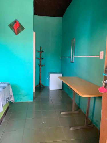 a room with a table and a green wall at Pousada Suíte Conexao in Conceição da Barra