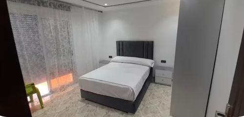 a white bedroom with a bed and a window at Apartamento dina 13 in Fnidek