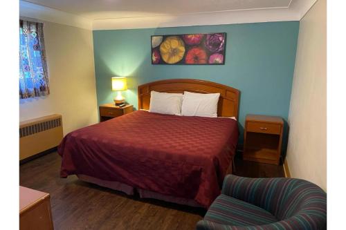 a hotel room with a bed and a chair at Queen's Motel Blenheim Near Lake Erie ON in Blenheim