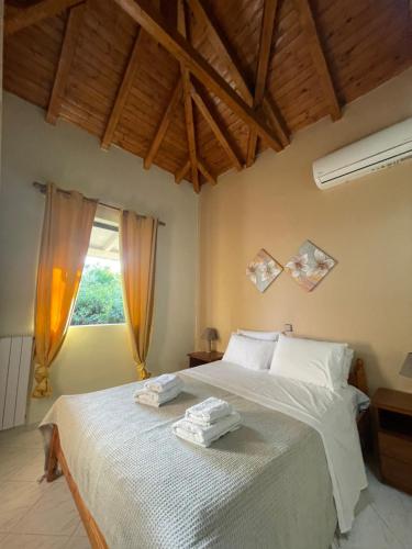 a bedroom with a bed with white sheets and a window at Olive & Sea Villa Koroni in Koroni