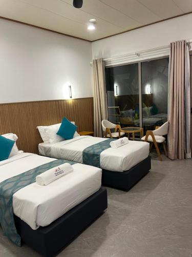 a hotel room with two beds and a living room at Tranquil Retreat Dhigurah in Dhigurah