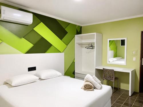a bedroom with a white bed and a green wall at Caruaru Pallace Hotel in Caruaru